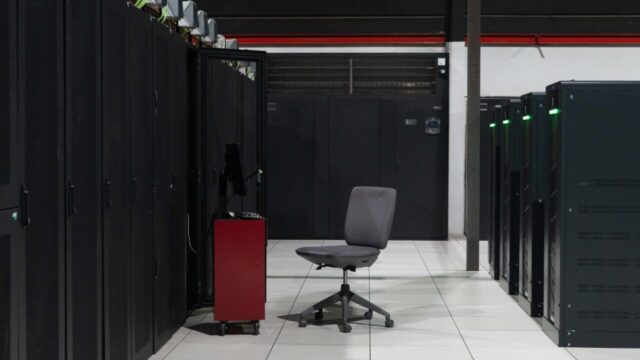 A system administrator’s workstation within a data processing centre with rack cabinets and servers inside.